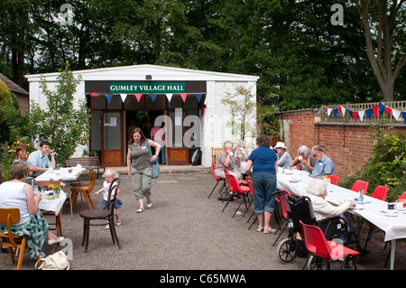 Menschen, die genießen einer Tasse Tee aus Seite Gumley Dorfhalle in Leicestershire während Dorf offene Gärten Veranstaltung. Stockfoto