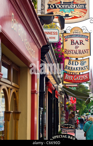 Die Zeichen außerhalb Geschäfte, Bars und Restaurants an einer Hauptstraße in Kenmare, County Kerry, Irland Stockfoto