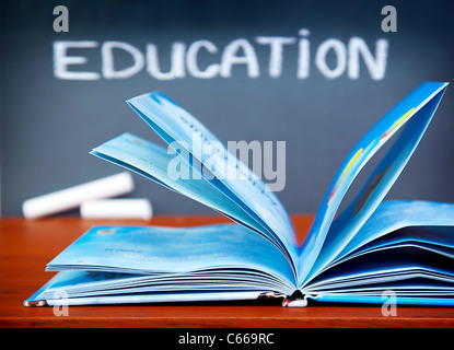 Bildungskonzept, offenes Buch auf dem Schreibtisch im Klassenzimmer, Tafel mit Bildung Word, zurück zur Schule Stockfoto