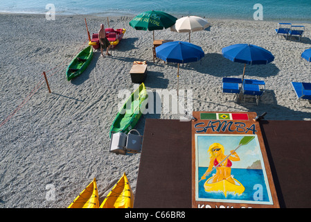 Ein einsamer Mann setzt sich Liegestühle und Sonnenschirme in den frühen Morgenstunden am Ligurischen Meer in Monterosso al Mare-Cinque Terre, Italien Stockfoto