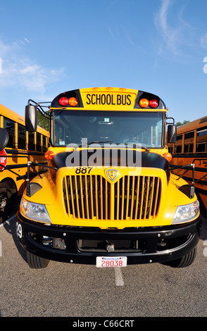 Frontal von ein gelben amerikanischer öffentlichen Schulbus umgeben von anderen geparkt Schulbusse stehen auf einem Parkplatz, USA. Stockfoto