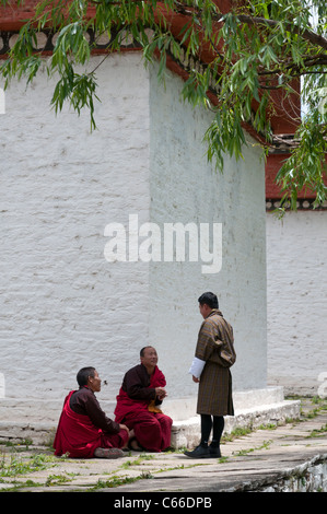 2 Mönche und Mann in Gho bei Chorten sprechen. Paro. Bhutan Stockfoto