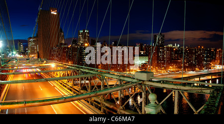 Panorama der Brooklyn Brücke hohen Verkehrsaufkommens in der Nacht und Manhattan Skyline mit Wolkenkratzern Stockfoto