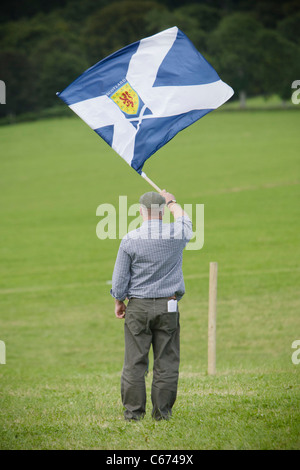 Mann steht im Feld winkt ein Andreaskreuz / St Andrews Cross - schottische Flagge Stockfoto