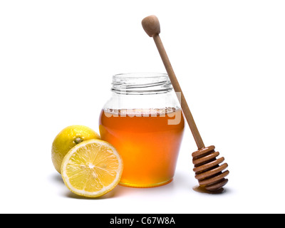 Glas Honig mit einem hölzernen Drizzler und Zitronen. Isoliert auf weißem Hintergrund. Stockfoto