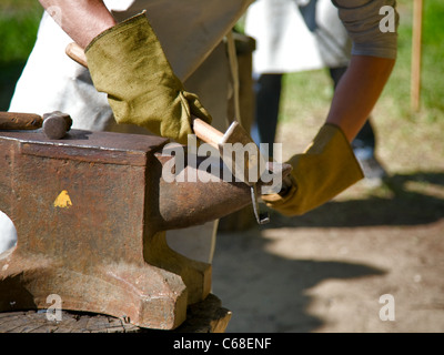 Händen der Schmied von Metallbearbeitung mit Hammer und Amboss. Hämmern glühenden Stahl - zu schmieden, solange das Eisen heiß ist. Stockfoto