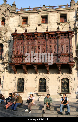 Menschen sitzen auf den Stufen des Palacio Arzobispal in der Plaza de Armas. Lima, Peru, Südamerika Stockfoto