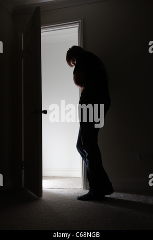 Mann, der durch eine offene Tür Kopf Licht aus dem Flur. Stockfoto