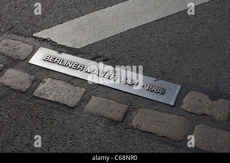 Eine Gedenktafel und Pflastersteine auf der Straße nahe dem Brandenburger Tor markieren die Lage der ehemaligen Mauer, die Berlin aufgeteilt. Stockfoto