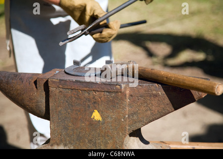 Händen der Schmied von Metallbearbeitung mit Hammer und Amboss. Hämmern glühenden Stahl - zu schmieden, solange das Eisen heiß ist. Stockfoto