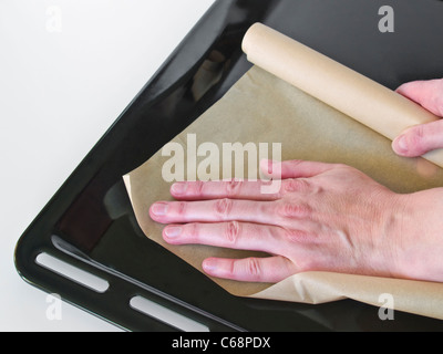 Auf Ein Backblech Wird Backpapier setzt | eine Person setzen etwas Backpapier auf ein Backblech Stockfoto