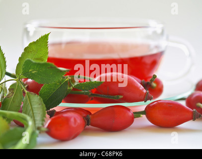 vorn sind eine Glasschale mit Hagebutten Tee, Hagebutte Stockfoto