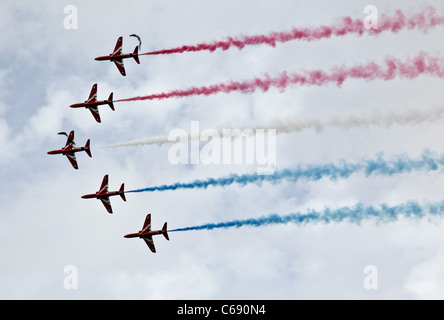 Die Red Arrows fliegen gegen ein bewölkter Himmel mit farbigen Rauch Stockfoto