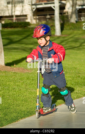 Tragen Jacke Pre-K Hispanic junge Reiten auf Scooter im Park. Herr © Myrleen Pearson Stockfoto