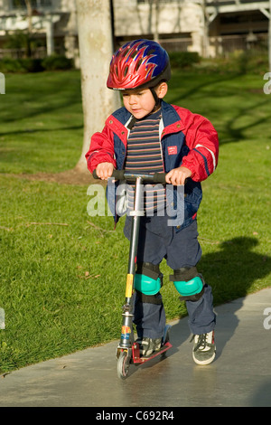 Tragen Jacke Pre-K Hispanic junge Reiten auf Scooter im Park. Herr © Myrleen Pearson Stockfoto