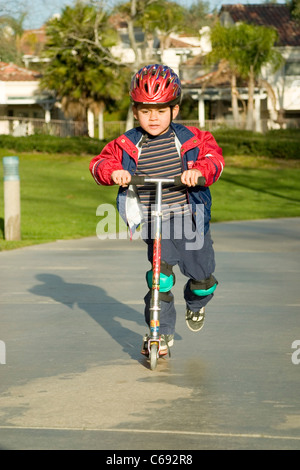 Pre-K Hispanic junge Reiten auf Scooter im Park. Herr © Myrleen Pearson Stockfoto