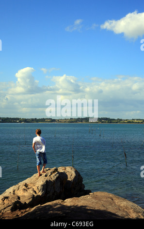 Junge stand auf Felsen betrachten des Golfe du Morbihan auf Ile de Berder, Larmor-Baden, Morbihan, Bretagne, Frankreich Stockfoto