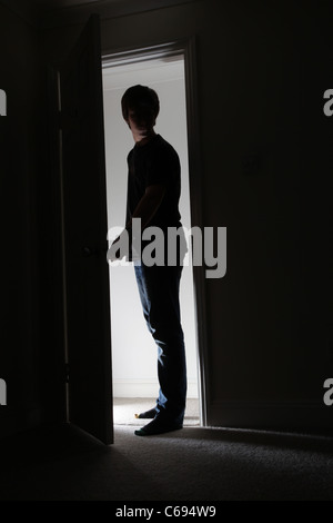 Mann, der in einer offenen Tür führt in einen dunklen Raum. Stockfoto