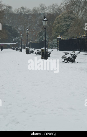 Hyde Park vor der Kensington Palace im Schnee mit Straßenlaternen und Parkbänke in Folge Stockfoto