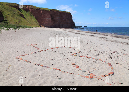 Amors Pfeil durch ein Herz besteht aus Steinen am North Beach auf der Insel Helgoland, Deutschland; Nordstrand Auf Helgoland Stockfoto