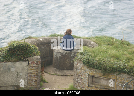 Mädchen sitzen auf der Suche heraus über Meer in St Mawes Castle, Süd Cornwall UK Stockfoto