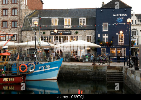 Die blaue-weiße Rumpf des FY95 Fischerboot und The Watering Hole spiegelt sich in dem Wasser bei Sutton Harbour, Barbican, Plymouth. Stockfoto