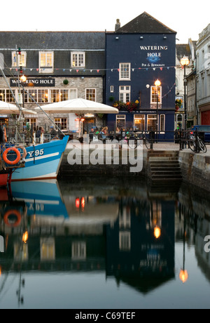 Die blaue-weiße Rumpf des FY95 Fischerboot und The Watering Hole spiegelt sich in dem Wasser bei Sutton Harbour, Barbican, Plymouth. Stockfoto