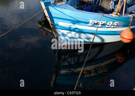 Die blaue-weiße Rumpf des FY95 Fischerboot in das Wasser am Plymouth Sutton Harbour, Barbican, wider. Stockfoto