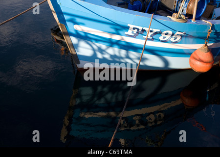 Die blaue-weiße Rumpf des FY95 Fischerboot in das Wasser am Plymouth Sutton Harbour, Barbican, wider. Stockfoto