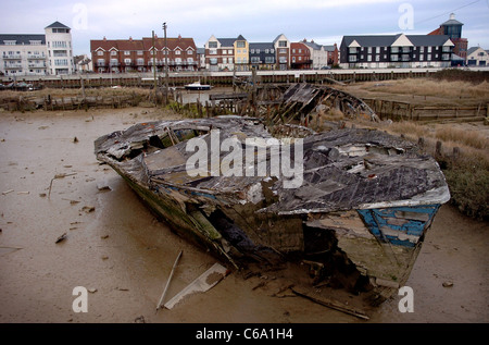 Die faulende Rumpf von einem alten Boot liegt im Schlamm am Fluss Arun mit neuen Littlehampton Hafen Kai UK Stockfoto