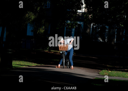 Ältere Frau, die ihr Fahrrad einstellen, London Fields Park, Hackney, London, UK Stockfoto