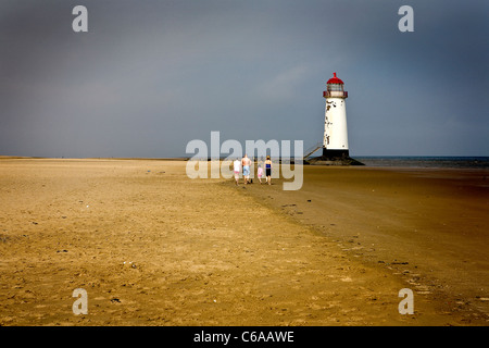 Menschen zu Fuß entlang des Strandes in der Nähe von Punkt von Ayr Leuchtturm auf Talacre Strand in Flintshire, Nordwales Stockfoto