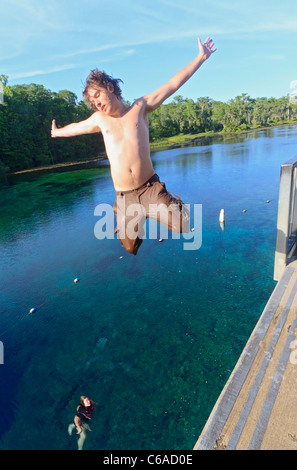 Junger Mann springt in Wakulla Frühling von hohen Plattform, während seine Freundin schaut Stockfoto