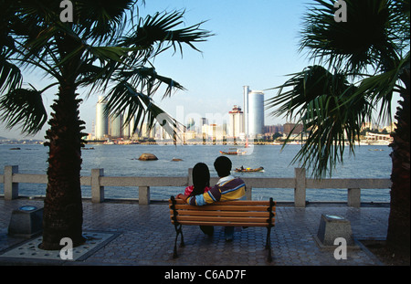 ein junges Paar auf Bank Blick auf Skyline von Xiamen China aus touristischen Insel Gulangyu China sitzen Stockfoto