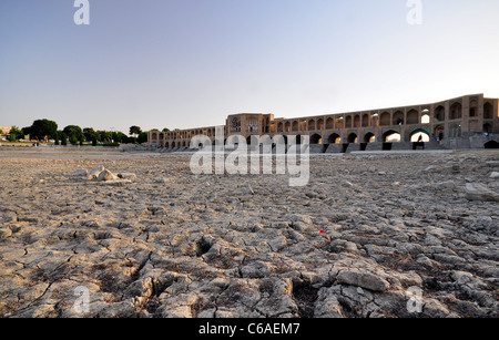 Das rissige Flussbett des Zayandeh Fluss aufgrund der sever Dürre und die Khaju-Brücke im Hintergrund in Isfahan, Iran. Stockfoto