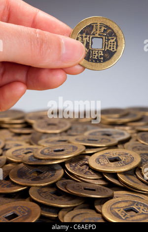 Hand, die traditionelle chinesische Münze über Stapel der Münzen Stockfoto