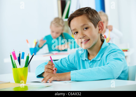 Porträt der süße Bursche zeichnen mit Klassenkameraden auf Hintergrund Stockfoto