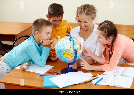 Porträt von niedlichen Schüler und Lehrer betrachten Globus im Klassenzimmer Stockfoto