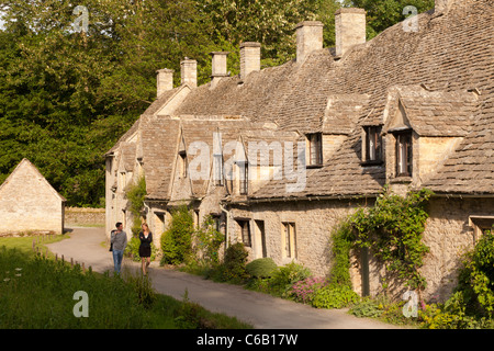 Ein junges Paar genießt einen Abendspaziergang neben der Arlington Row im Cotswold-Dorf Bibury, Gloucestershire, Großbritannien Stockfoto