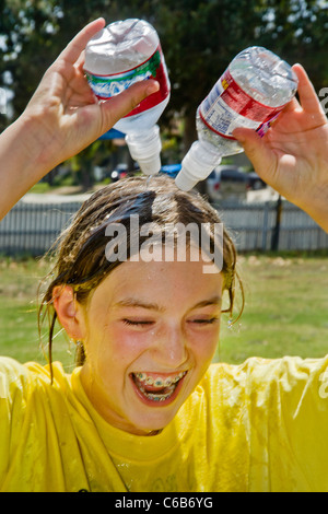 Ein Teenager-Mädchen gießt kaltes Wasser über sich selbst an einem heißen Nachmittag in Orange, Kalifornien. Stockfoto