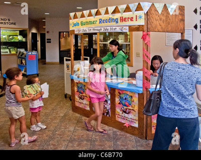 Asiatisch-amerikanische Freiwillige beraten Sommer Lesung lateinamerikanische und asiatische Kinder in einer öffentlichen Bibliothek in Aliso Viejo, CA. Stockfoto