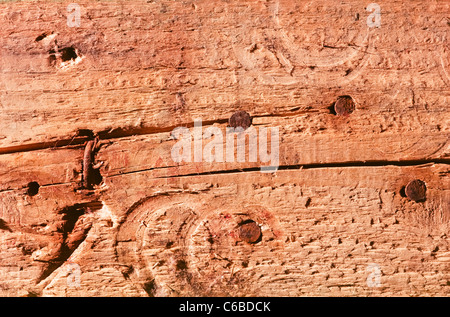 Detail einer heruntergekommenen hölzerne Diele zeigt Risse und eine Reihe von rostigen Nailheads. Stockfoto