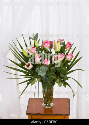 Ein Bouquet von rosa Rosen und Lilien in einer Vase auf dem Tisch Stockfoto