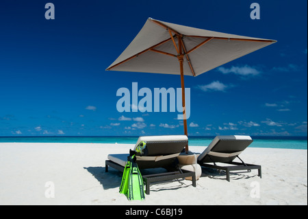 Flossen und Liegestühlen im Schatten der Sonnenschirm am Strand, Nord-Huvadhoo-Atoll, Malediven Stockfoto