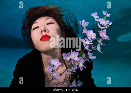 Frau im Kimono Blumen unter Wasser halten Stockfoto