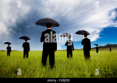 Kaufmann im schwarzen Anzug hält Regenschirm und beobachten der Sturm kommt Stockfoto