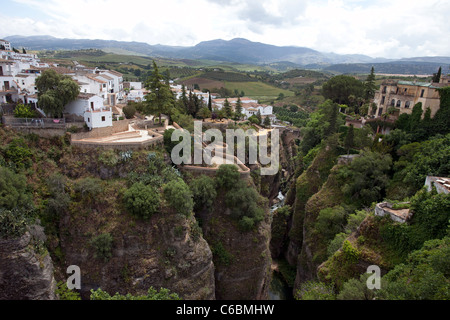 Historische Brücke über die tiefe Schlucht nach Ronda Spain mit Restaurant im Freien. Hotels und Apartments am Rand der steilen Klippe. Stockfoto