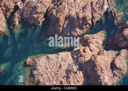 LUFTAUFNAHME. Paar Kajakfahren in einem schmalen Wasserweg in einer Landschaft aus rotem Vulkangestein. Esterel-Massiv, Cap Dramont, Saint Raphaël. Französische Riviera. Stockfoto