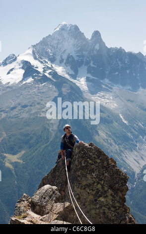 Eine männliche Kletterer auf einem Gipfeltreffen in Chamonix mit Grandes Montets im Hintergrund Stockfoto