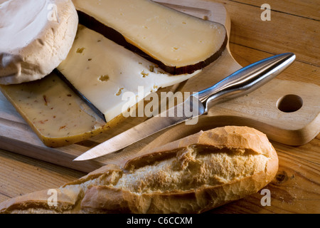 Auswahl an Käse, Brot und Messer auf hölzernen Käseplatte Stockfoto